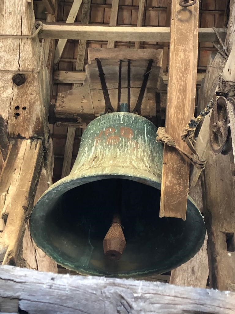 La cloche de bronze de 1544 suspendue dans son beffroi de bois sous le clocher