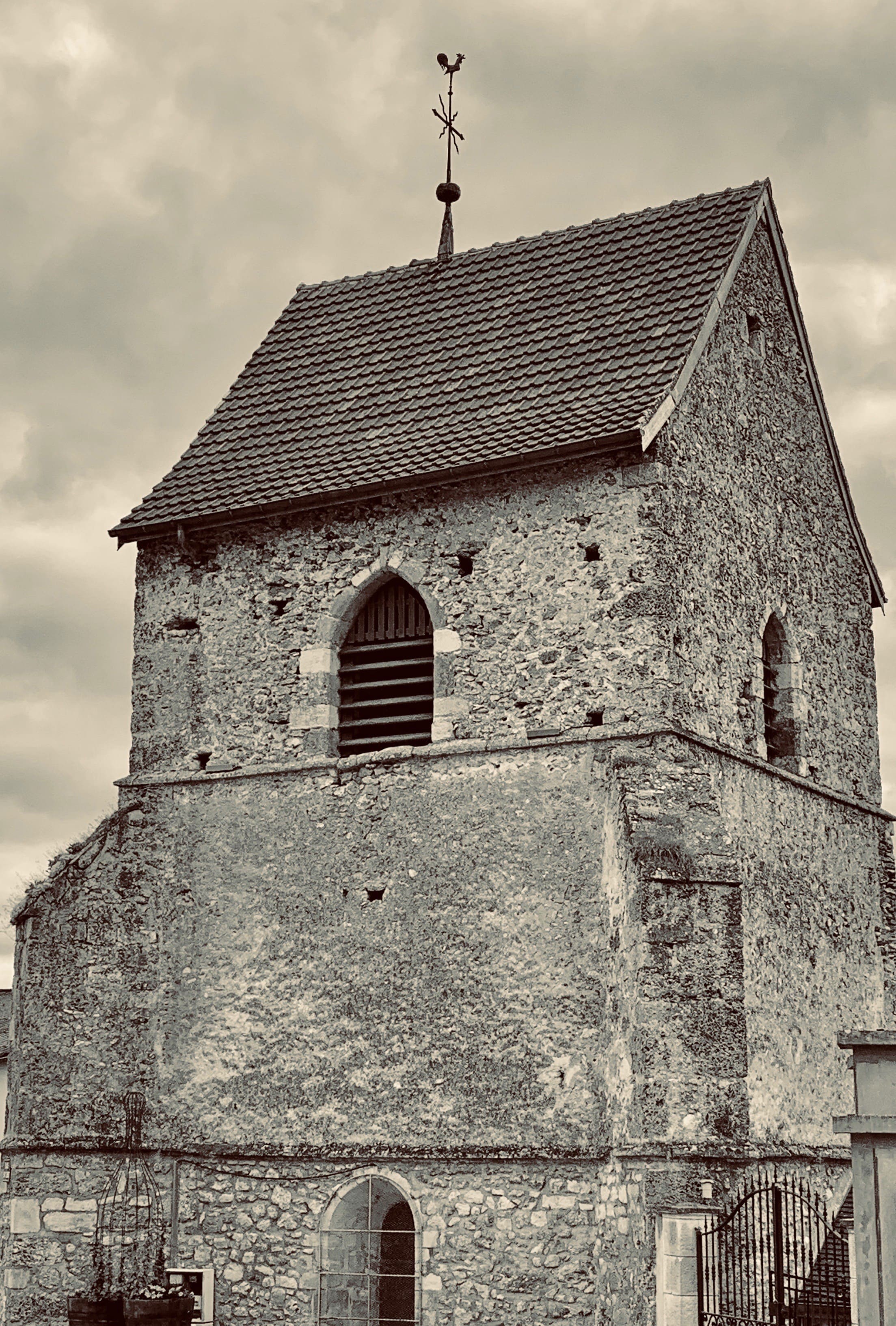 Le clocher de l'église Saint-Clément en gros plan, avec son coq et sa croix