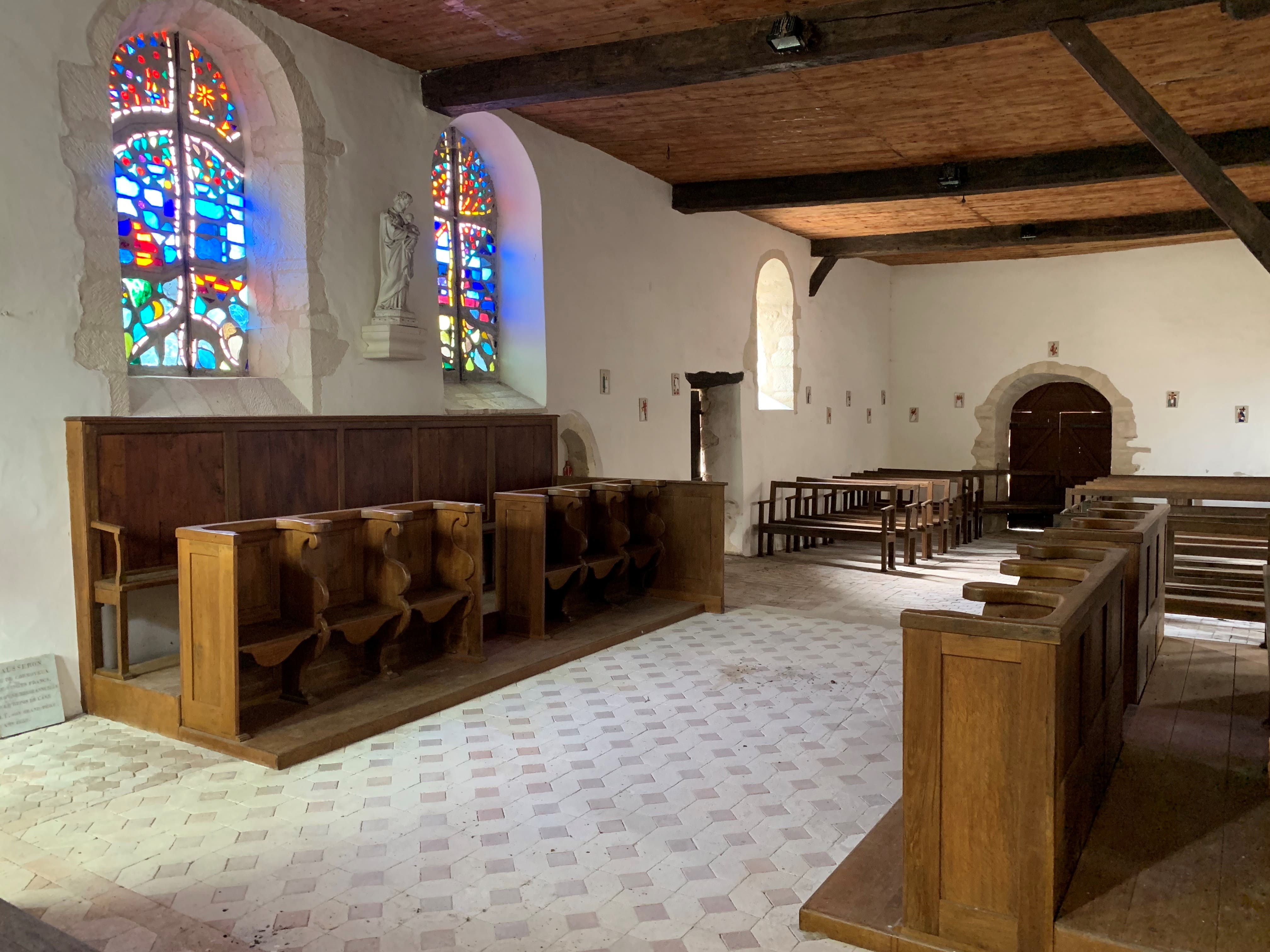 Intérieur de la nef baignée par la lumière colorée des vitraux contemporains