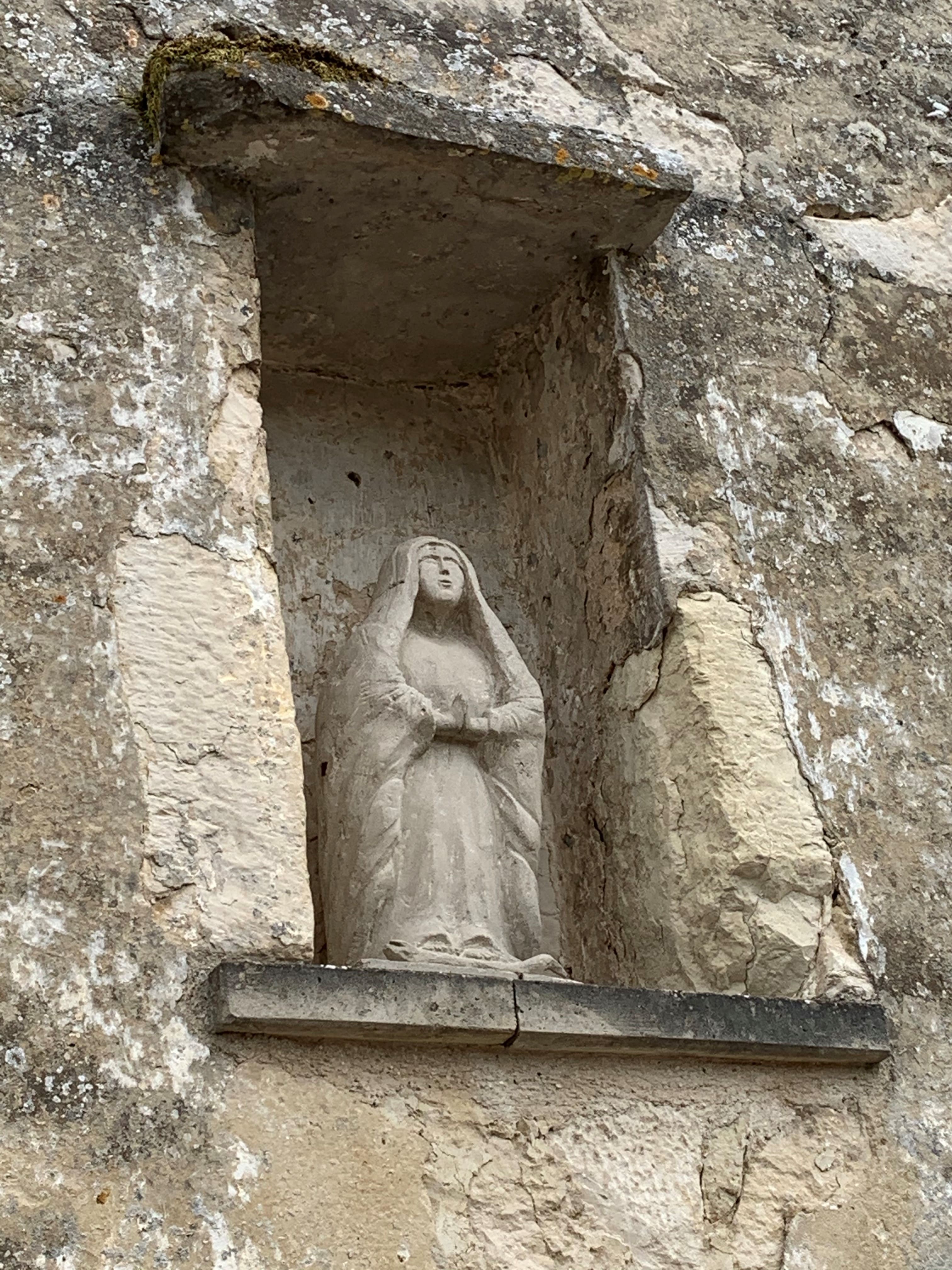 Niche de pierre abritant une statue de Vierge orante