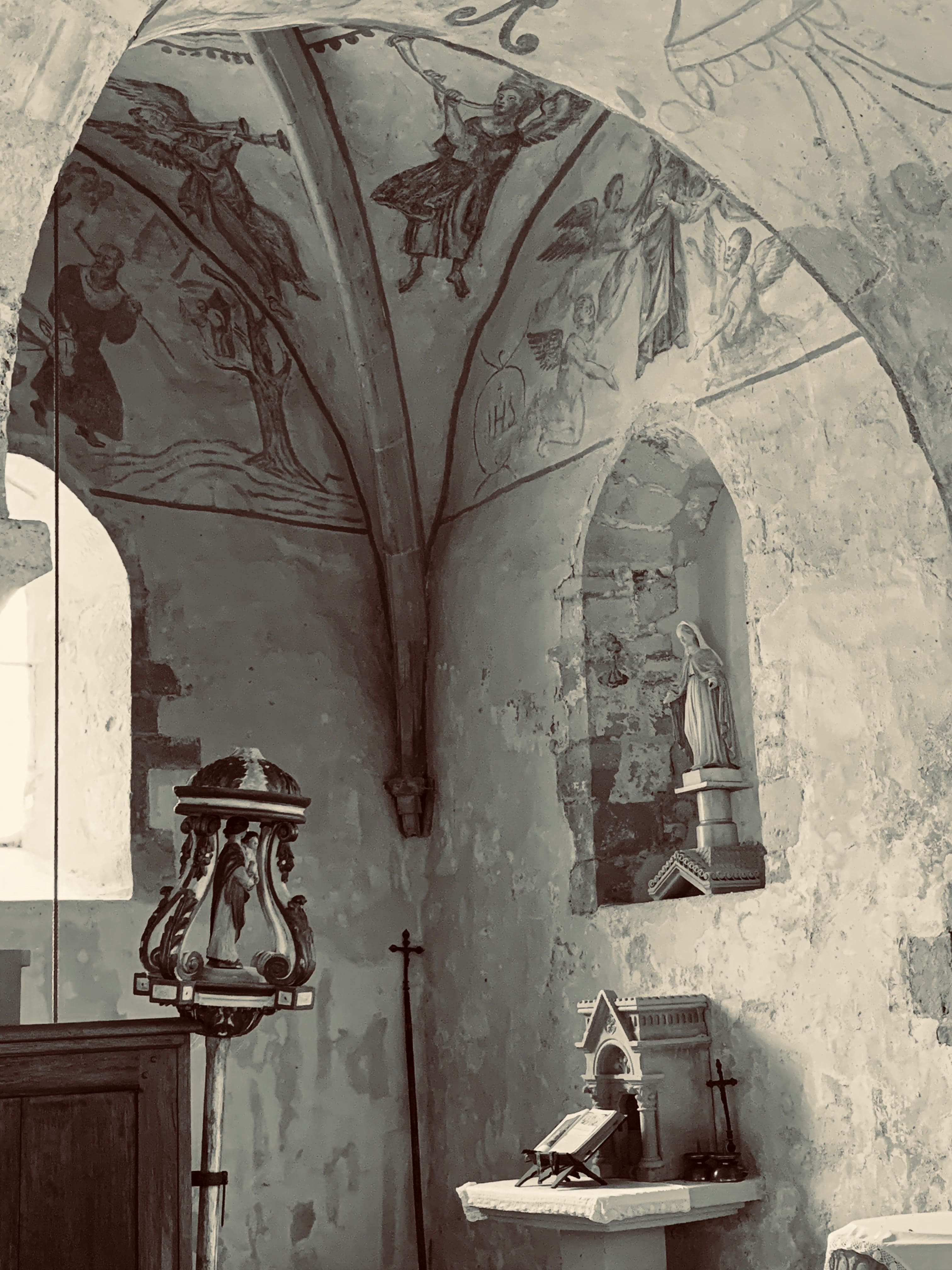 Transept nord avec fresques, niche à statue mariale et fonts baptismaux