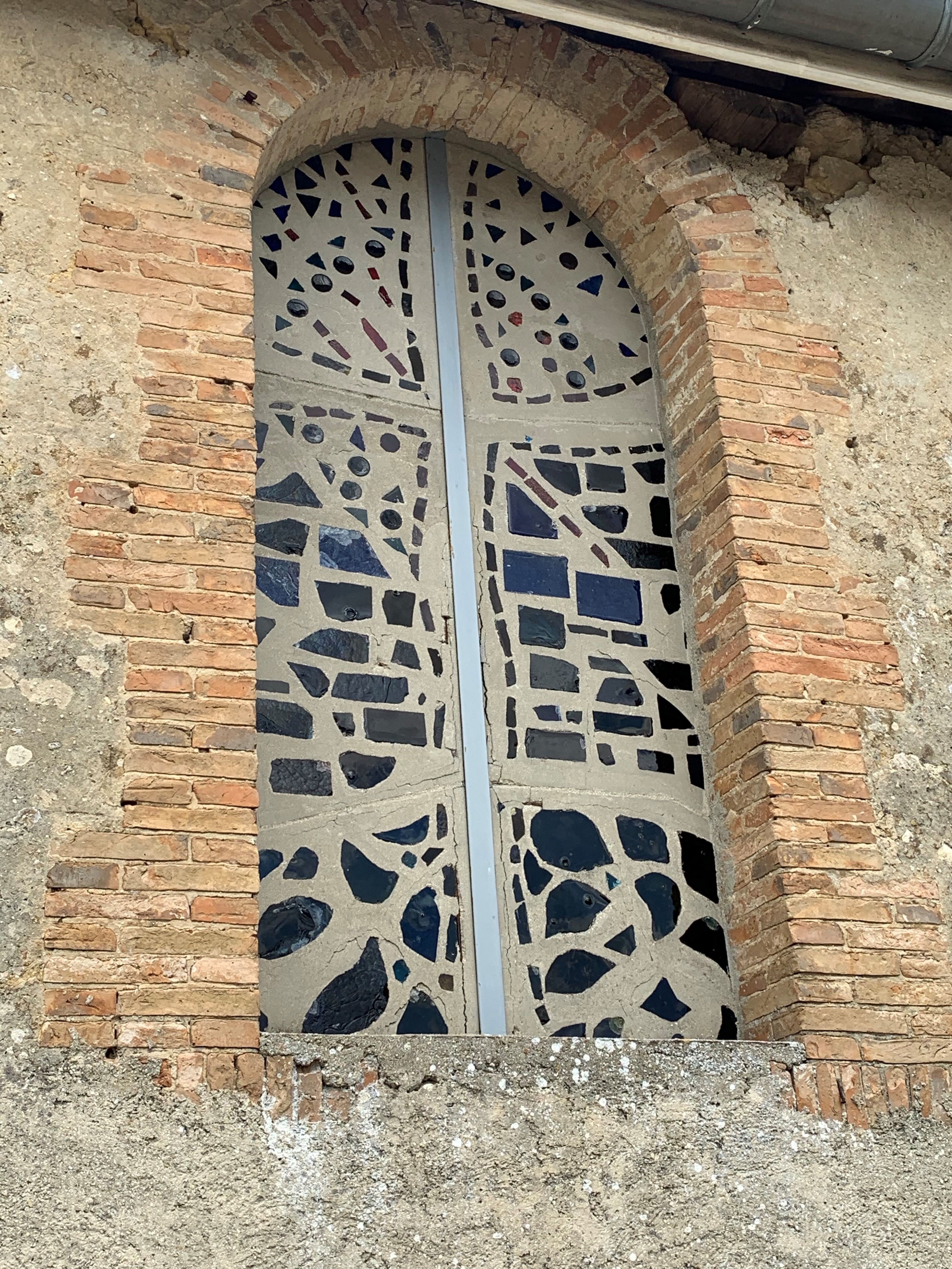 Vitrail en mosaïque de verre cassé encadrée de briques rouges